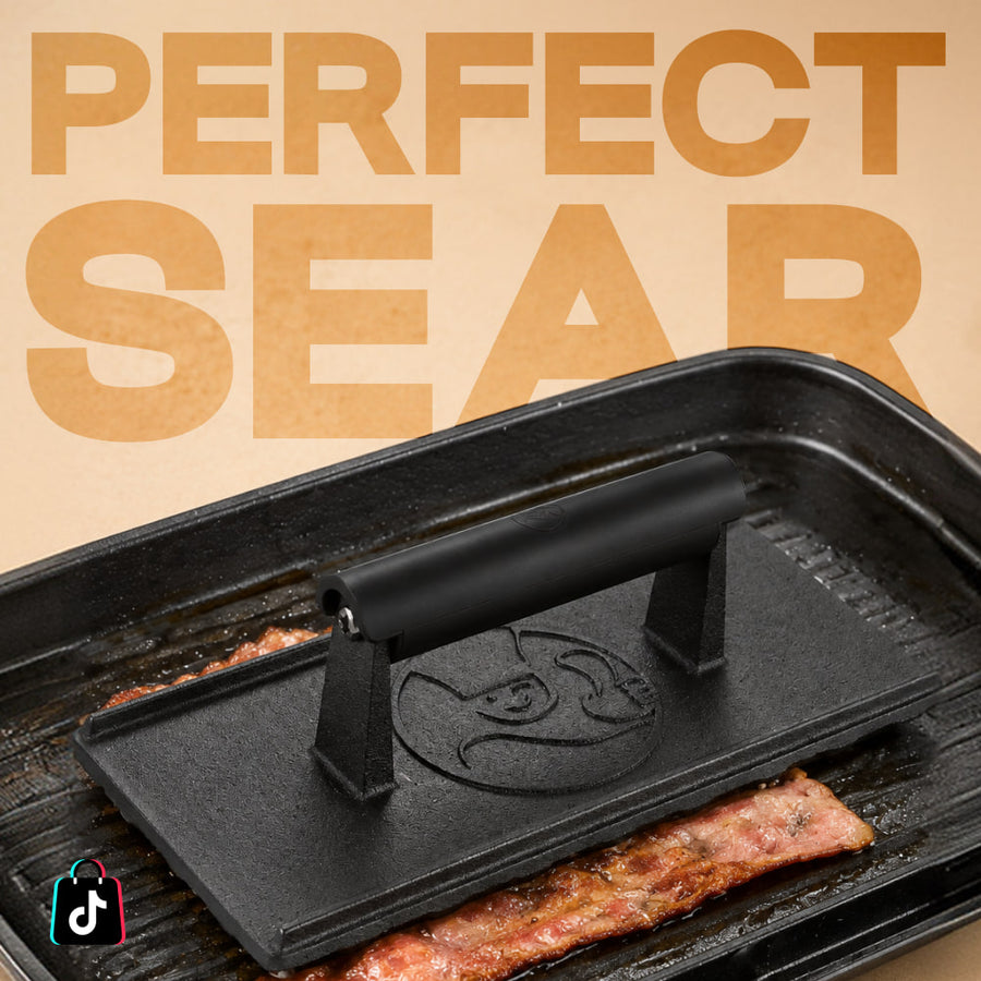 Cast iron grill press searing bacon on a barbecue